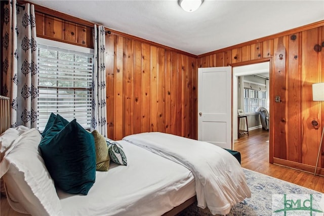 bedroom featuring wooden walls, light hardwood / wood-style flooring, and crown molding