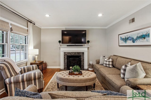 living room featuring hardwood / wood-style flooring, crown molding, and a fireplace