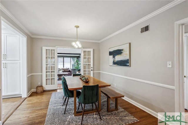 dining area featuring a chandelier, french doors, light hardwood / wood-style flooring, and ornamental molding