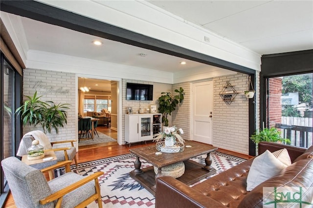 living room with hardwood / wood-style floors, a wealth of natural light, and brick wall