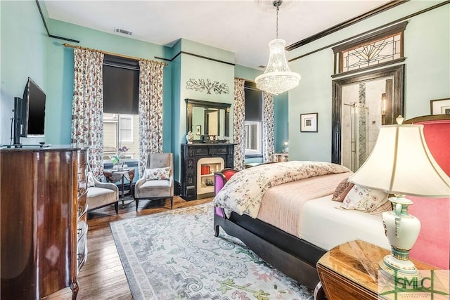 bedroom featuring dark hardwood / wood-style floors, crown molding, and a notable chandelier