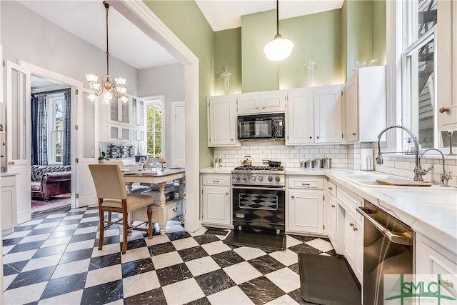 kitchen featuring white cabinetry, sink, a chandelier, decorative light fixtures, and black appliances