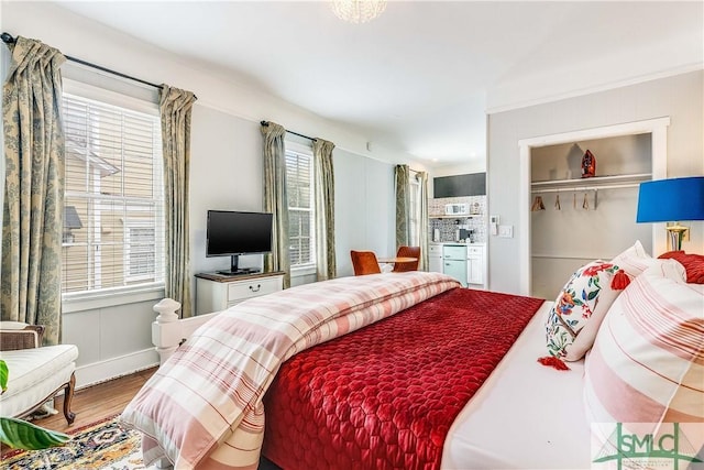 bedroom with hardwood / wood-style floors, a closet, and multiple windows