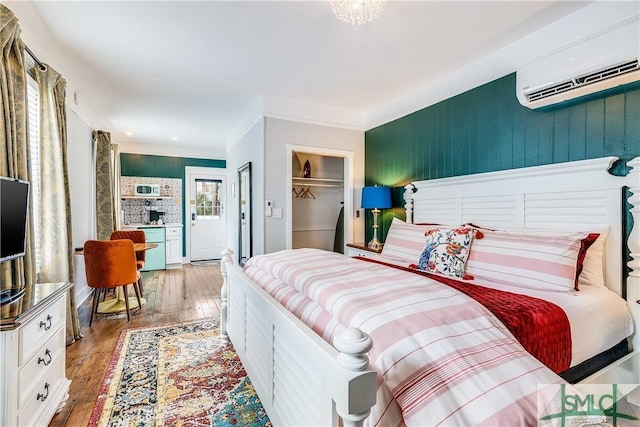 bedroom featuring wood-type flooring, a wall unit AC, a closet, and crown molding