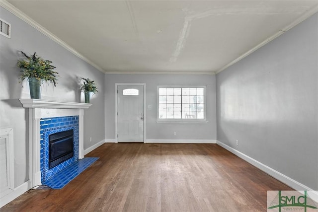 unfurnished living room with hardwood / wood-style flooring, ornamental molding, and a tiled fireplace