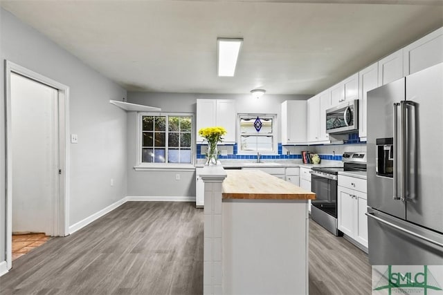 kitchen with wooden counters, tasteful backsplash, stainless steel appliances, sink, and white cabinets