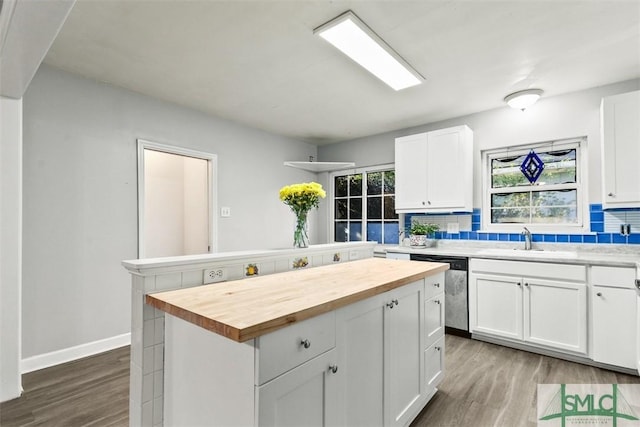 kitchen featuring wooden counters, sink, decorative backsplash, a kitchen island, and white cabinetry