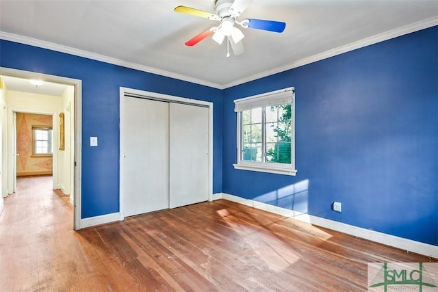 unfurnished bedroom with wood-type flooring, a closet, ceiling fan, and crown molding