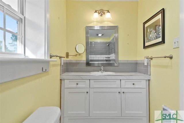 bathroom with a shower, decorative backsplash, vanity, and toilet