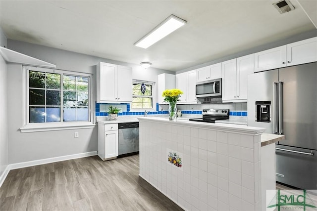 kitchen with white cabinets, backsplash, a kitchen island, and stainless steel appliances