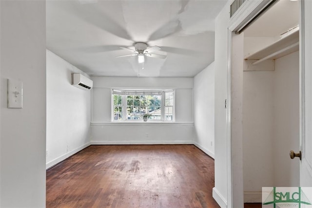 empty room with a wall unit AC, ceiling fan, and dark wood-type flooring