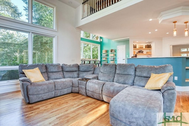 living room with built in shelves, light wood-type flooring, and a healthy amount of sunlight