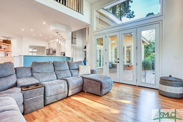 living room with light wood-type flooring, a high ceiling, and french doors