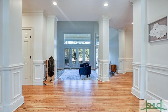 interior space featuring french doors, light hardwood / wood-style floors, decorative columns, and ornamental molding