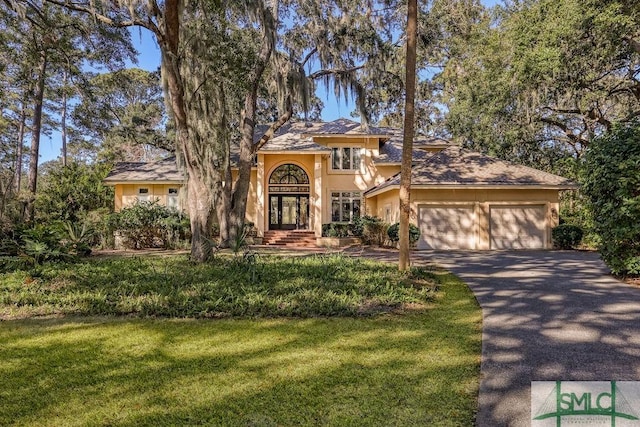 mediterranean / spanish-style home featuring french doors, a garage, and a front lawn