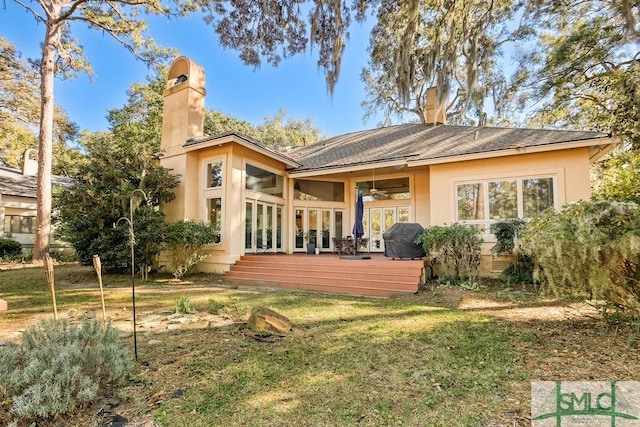 rear view of property with a lawn, a wooden deck, ceiling fan, and a sunroom