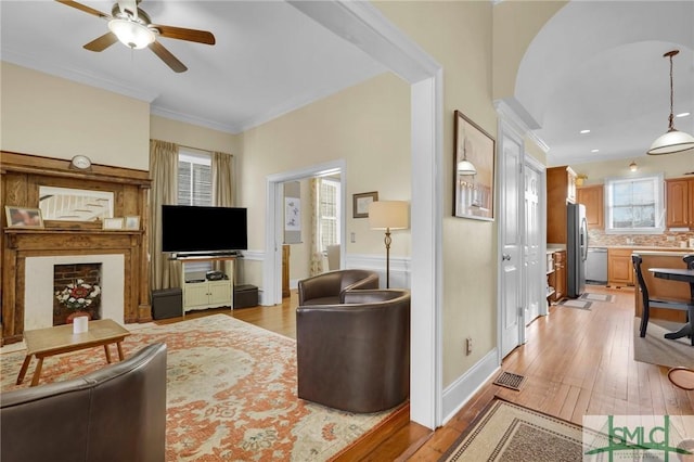 living room featuring crown molding, ceiling fan, and light wood-type flooring