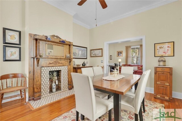 dining area featuring ceiling fan, light hardwood / wood-style floors, crown molding, and a fireplace