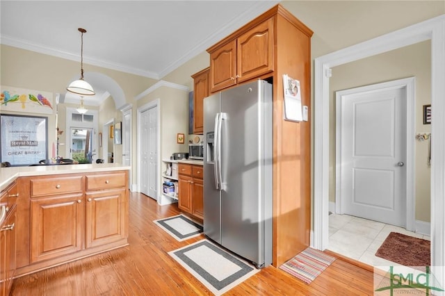 kitchen featuring decorative light fixtures, stainless steel appliances, light hardwood / wood-style flooring, and ornamental molding