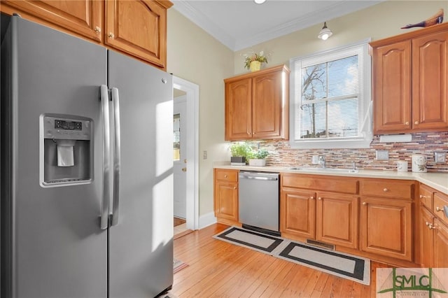 kitchen with stainless steel appliances, tasteful backsplash, ornamental molding, and sink