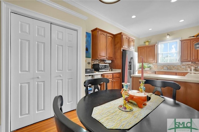 kitchen with decorative backsplash, stainless steel refrigerator with ice dispenser, light wood-type flooring, and ornamental molding