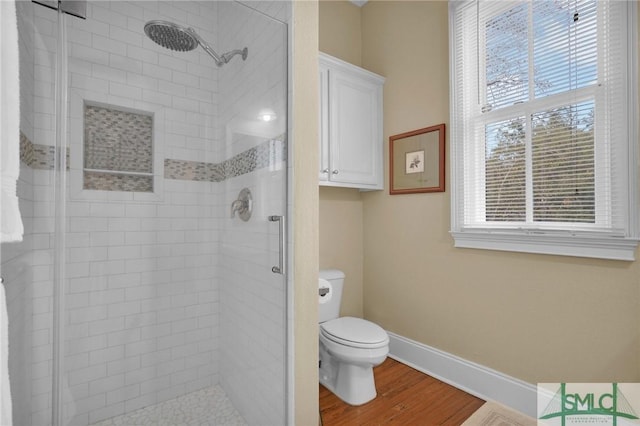 bathroom with toilet, a shower with shower door, and hardwood / wood-style flooring