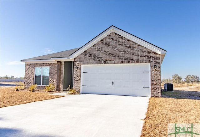 ranch-style home with concrete driveway, brick siding, central AC, and an attached garage