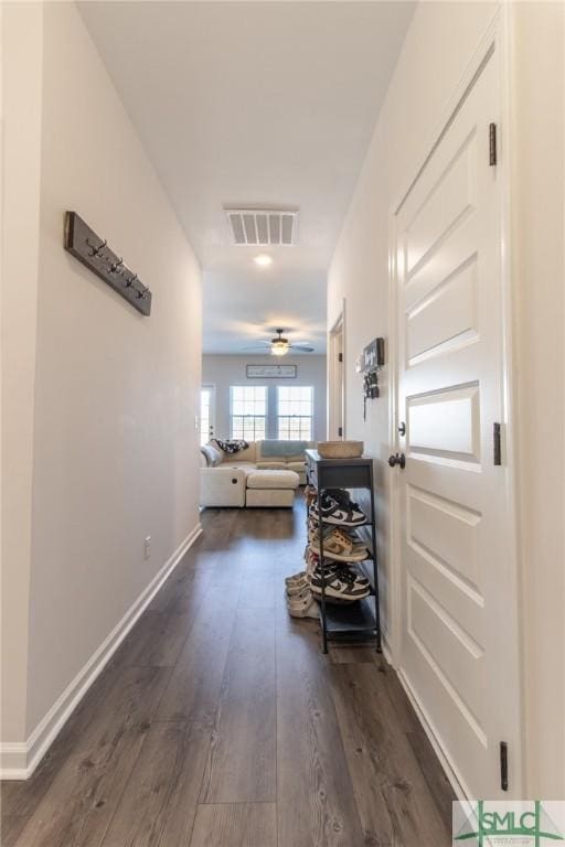 corridor featuring visible vents, dark wood finished floors, and baseboards