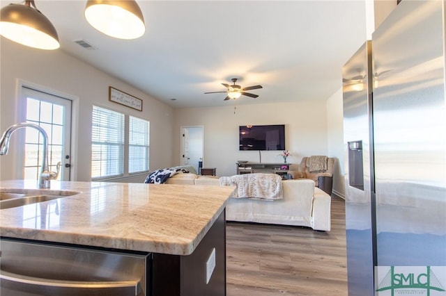 kitchen with visible vents, ceiling fan, wood finished floors, stainless steel appliances, and a sink