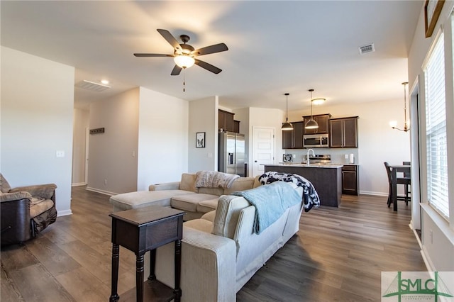 living room with baseboards, visible vents, dark wood finished floors, and a ceiling fan