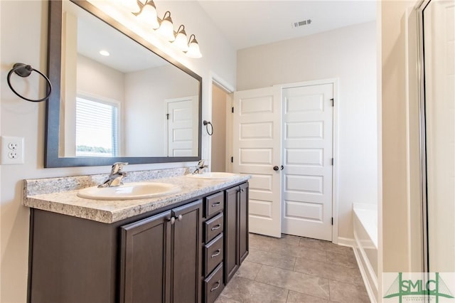 full bath with a tub to relax in, visible vents, a sink, and double vanity