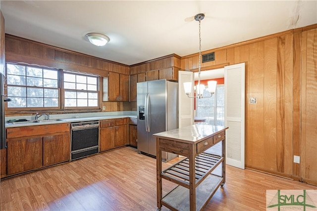 kitchen with sink, black dishwasher, stainless steel fridge, a chandelier, and decorative light fixtures