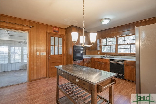 kitchen featuring wooden walls, pendant lighting, black appliances, and sink