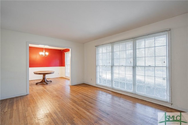 unfurnished room featuring light hardwood / wood-style flooring and a notable chandelier