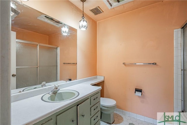 bathroom featuring vanity, toilet, and a shower with shower door