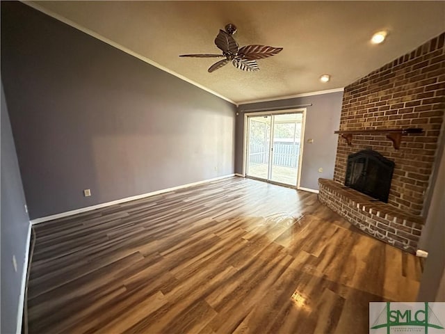 unfurnished living room featuring vaulted ceiling, ceiling fan, crown molding, wood-type flooring, and a fireplace