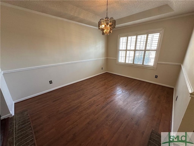 unfurnished room featuring a tray ceiling, dark wood-type flooring, a textured ceiling, and an inviting chandelier