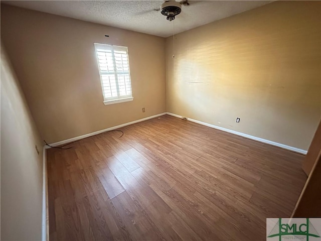 unfurnished room with ceiling fan, wood-type flooring, and a textured ceiling