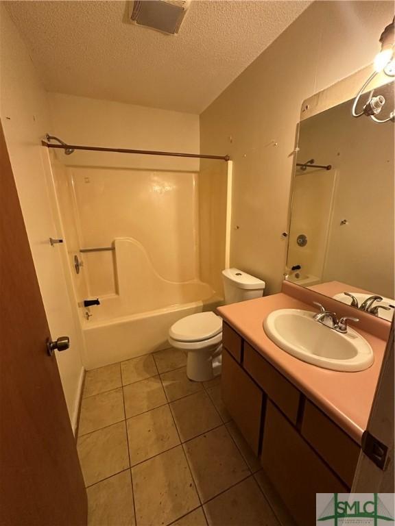 full bathroom with washtub / shower combination, tile patterned floors, a textured ceiling, and toilet