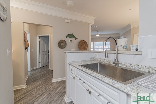 kitchen with light stone counters, crown molding, sink, hardwood / wood-style flooring, and white cabinets