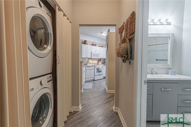 laundry room with dark hardwood / wood-style flooring, crown molding, stacked washer and clothes dryer, and sink