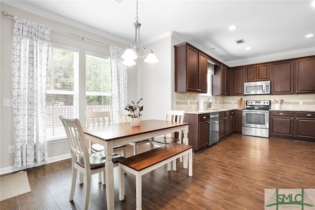 kitchen with sink, a chandelier, decorative light fixtures, appliances with stainless steel finishes, and ornamental molding