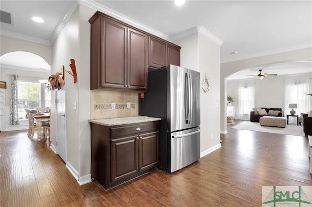 kitchen featuring ceiling fan, stainless steel fridge, ornamental molding, tasteful backsplash, and dark brown cabinetry