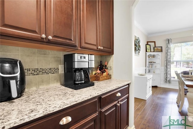 kitchen featuring decorative backsplash, dark hardwood / wood-style floors, light stone counters, and crown molding