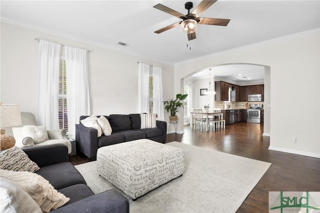 living room with ceiling fan, a healthy amount of sunlight, dark hardwood / wood-style flooring, and ornamental molding