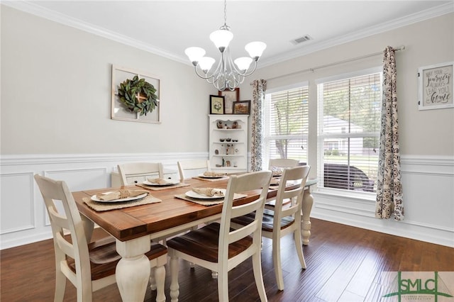 dining room featuring dark hardwood / wood-style floors, crown molding, and an inviting chandelier