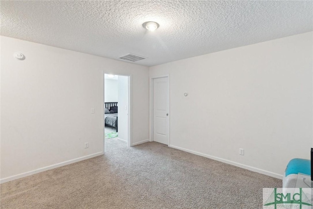 unfurnished room with a textured ceiling and light carpet