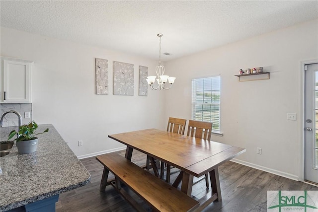 dining area featuring a textured ceiling, dark hardwood / wood-style floors, and a notable chandelier