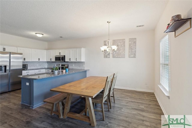 kitchen featuring dark stone counters, white cabinets, hanging light fixtures, appliances with stainless steel finishes, and kitchen peninsula