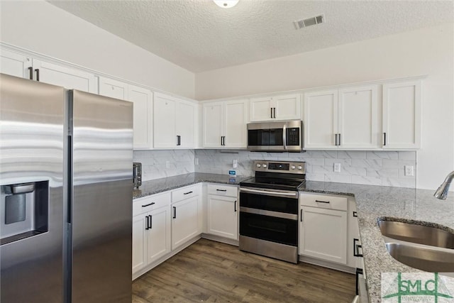 kitchen featuring white cabinets, appliances with stainless steel finishes, light stone counters, and sink